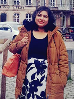sayantini some wearing a brown coat smiling 